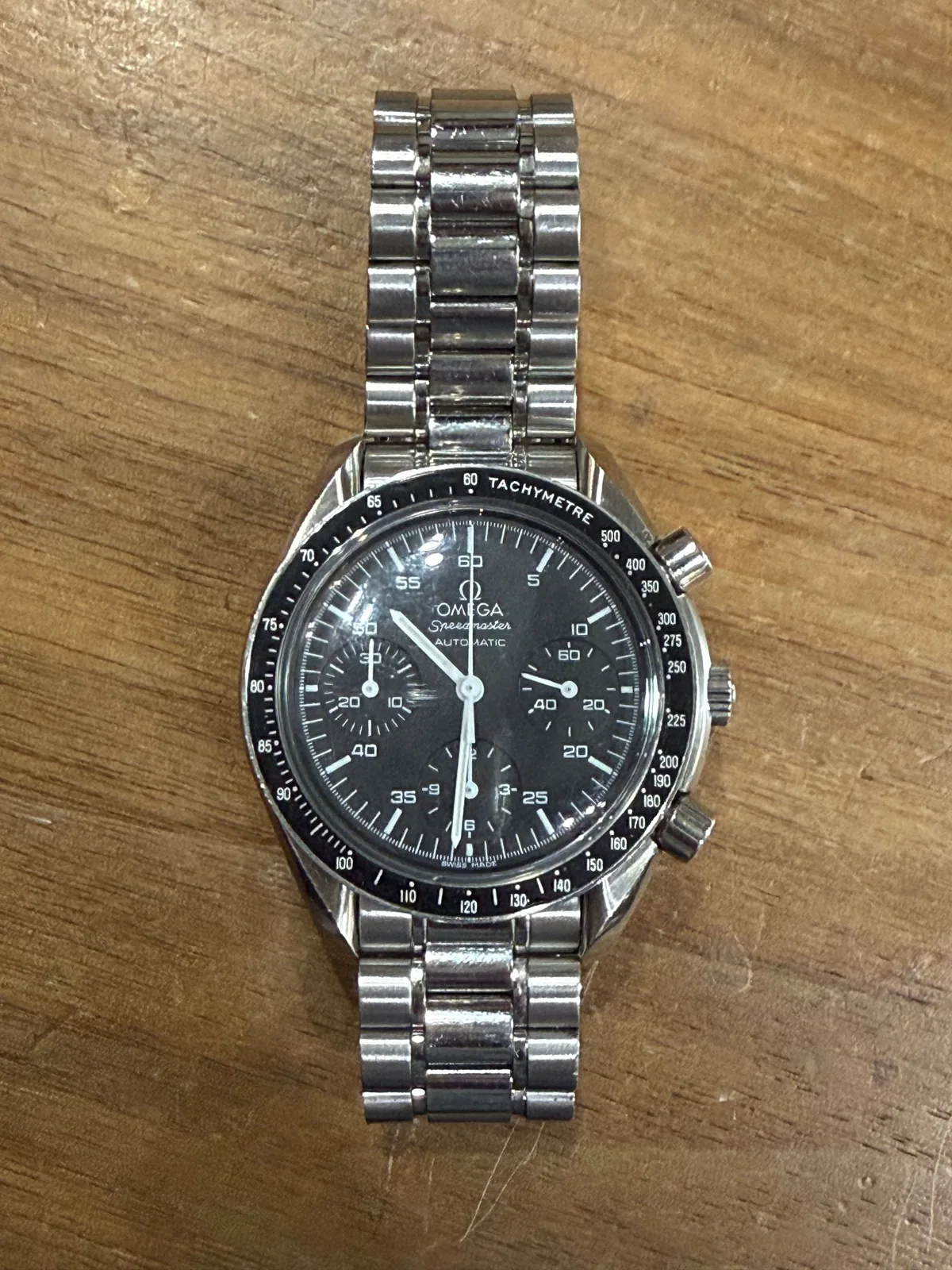 A steel chronograph watch on the bench after service
